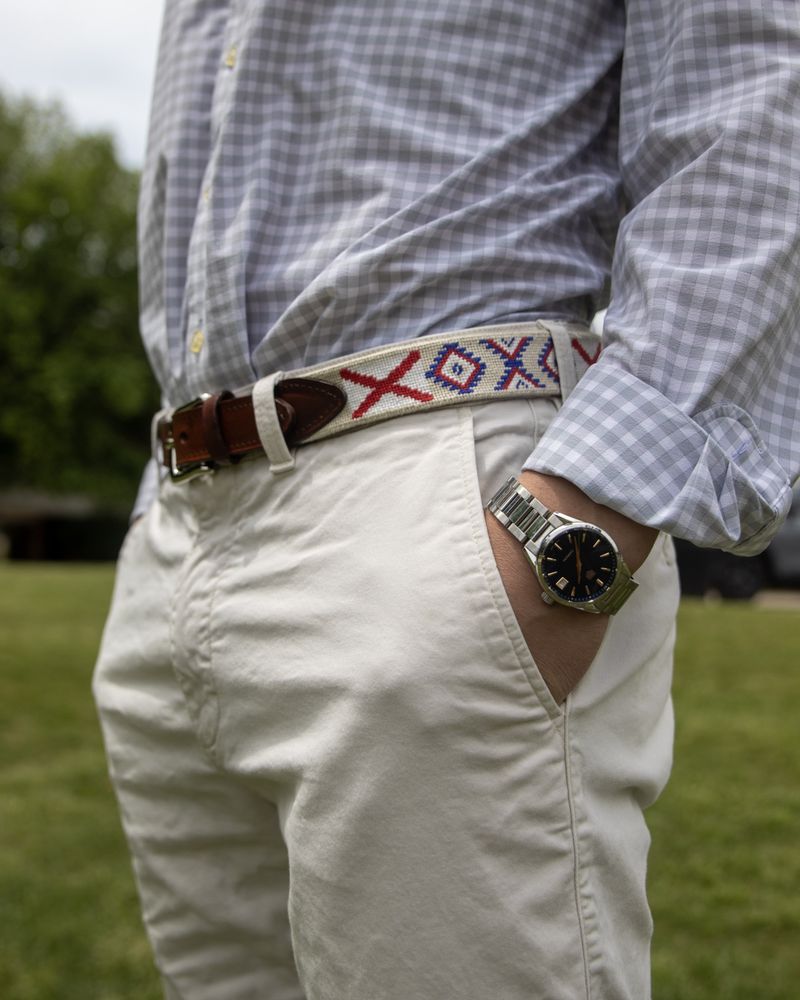 Close detail of a beaded belt, khakis, and a watch